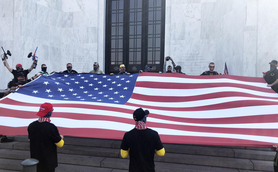 Right-wing protesters unfurl a flag on the steps of Oregon State Capitol for a pro-Donald Trump rally at the Capitol in Salem, Ore. on Monday, Sept. 7, 2020. (AP Photo/Andrew Selsky)