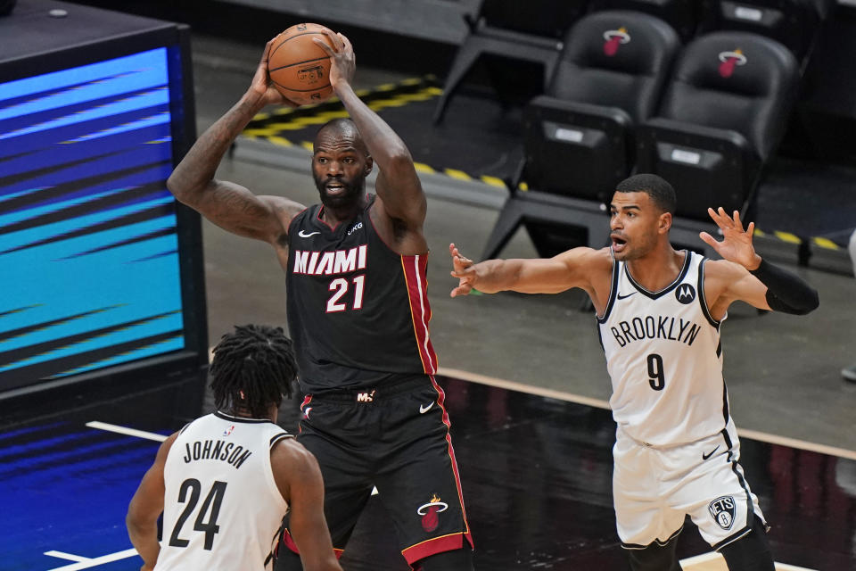 Miami Heat center Dewayne Dedmon (21) passes the ball past Brooklyn Nets forward Alize Johnson (24) and guard Timothe Luwawu-Cabarrot (9) during the first half of an NBA basketball game, Sunday, April 18, 2021, in Miami. (AP Photo/Wilfredo Lee)