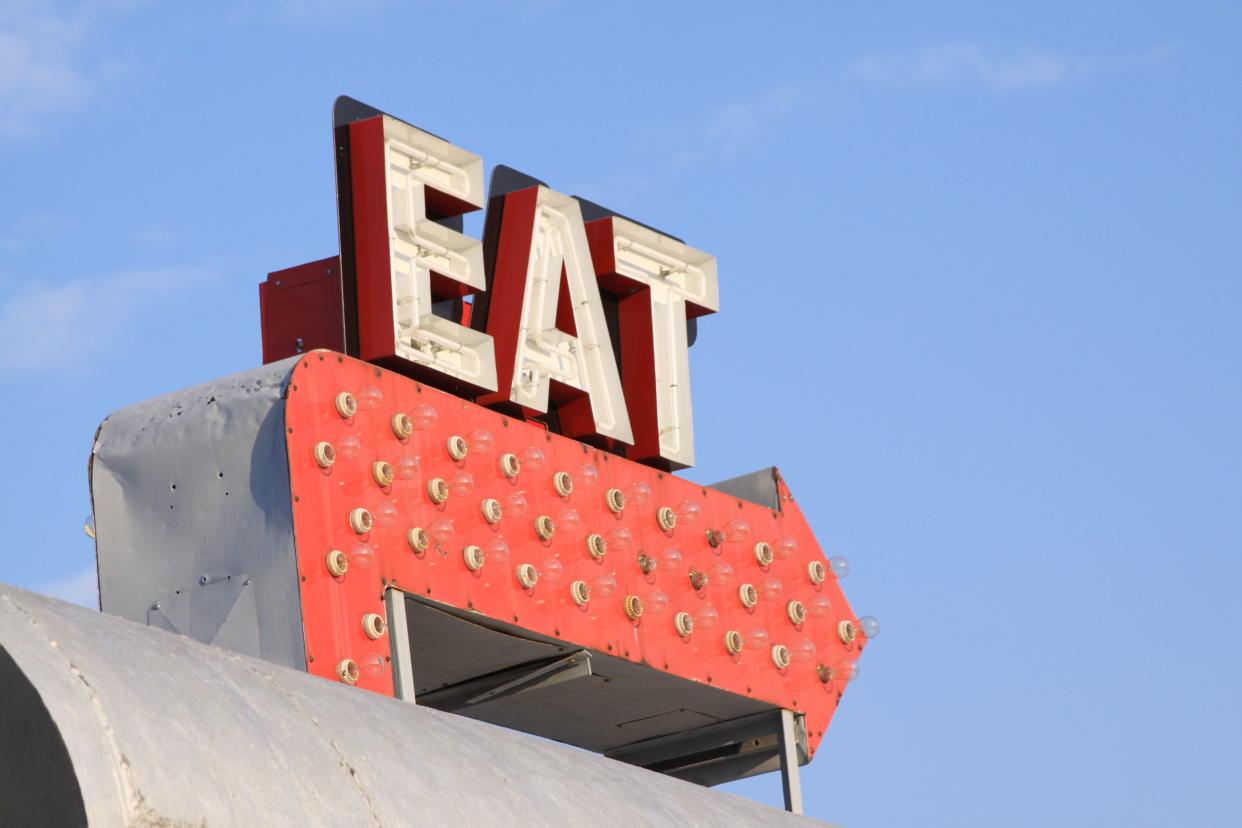 Retro sign from an old diner is photographed against a blue sky.