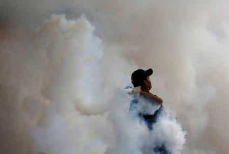 An opposition supporter throws back a tear gas canister during clashes with security forces at a protest against President Nicolas Maduro in Caracas, Venezuela May 4, 2017. REUTERS/Carlos Garcia Rawlins