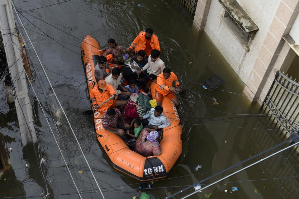 National Disaster Response Force (NDRF) personnel evacuate local residents in a boat along a flooded street following heavy rains in Hyderabad on October 15, 2020. (Photo by NOAH SEELAM / AFP) (Photo by NOAH SEELAM/AFP via Getty Images)