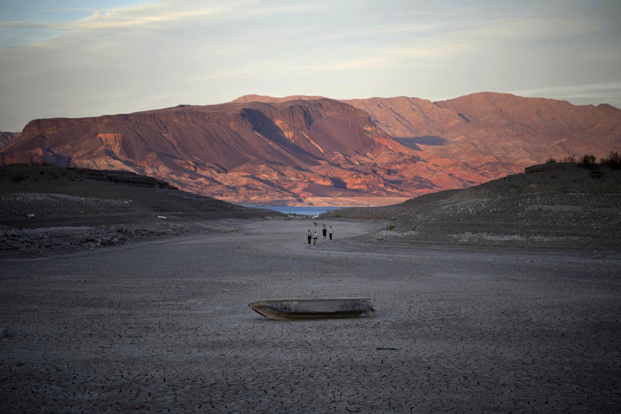 People walk towards a formerly sunken boat on cracked earth hundreds of feet from what is now the shoreline on Lake Mead at the Lake Mead National Recreation Area, near Boulder City, Nev. (John Locher/AP)