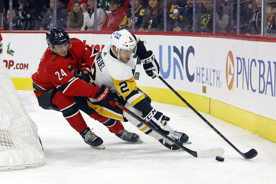 Carolina Hurricanes' Seth Jarvis (24) battles Pittsburgh Penguins' Chad Ruhwedel (2) during the second period of an NHL hockey game in Raleigh, N.C., Sunday, Dec. 18, 2022. (AP Photo/Karl B DeBlaker)