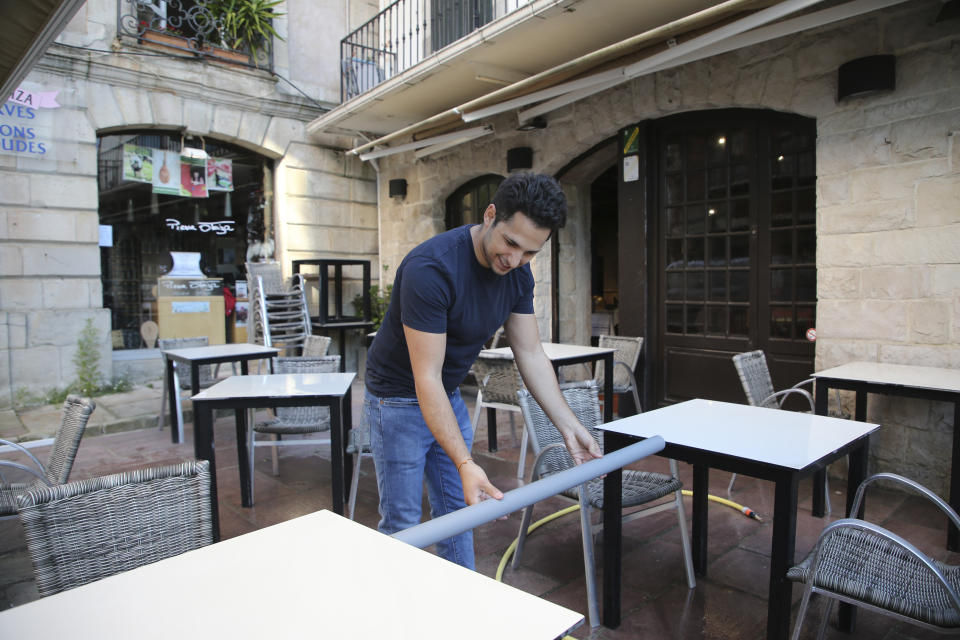 A restaurant employee measures the distance between two tables in a restaurant of Saint-Jean-de-Luz, southwestern France, Friday May 29, 2020. From June 2 restaurants and cafes will reopen, together with monuments and museums, concert halls and theaters, beaches, campsites, gyms and public swimming pools. There's a notable exception for the Paris region, the country's worst-affected by the virus, where many facilities will have to wait until June 22 to reopen. (AP Photo/Bob Edme)