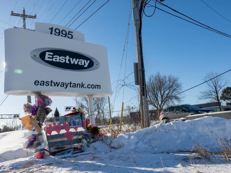 A growing tribute of flowers, cards and other items left in memory of the victims of the deadly explosion and fire at Eastway Tank is seen outside the Merivale Road manufacturing plant on Jan. 20, 2022, one week after the blast. (Francis Ferland/CBC - image credit)