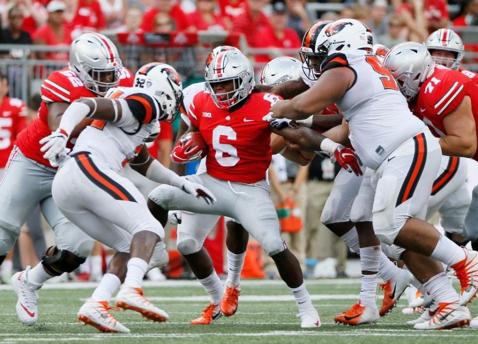 Ohio State Buckeyes running back Brian Snead (6) runs between tackle attempts by Oregon State Beavers linebacker Jonathan Willis (32) and defensive tackle Elu Aydon (99) during the fourth quarter of the NCAA football game at Ohio Stadium in Columbus on Sept. 1, 2018. Ohio State won 77-31.