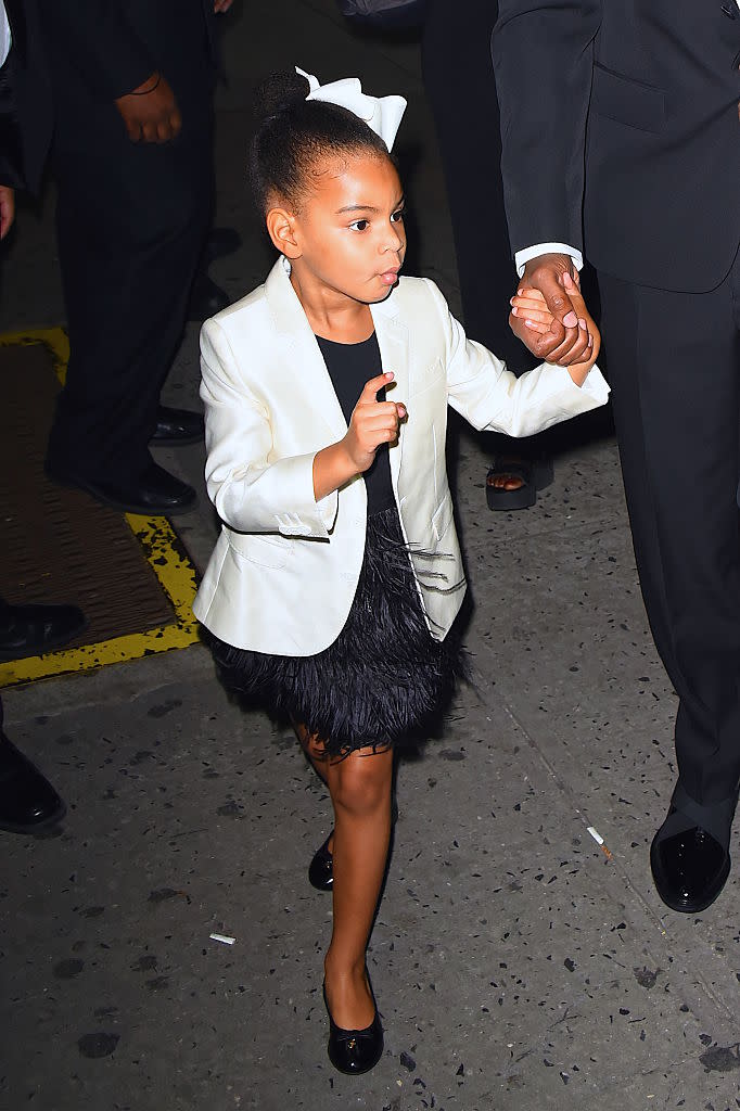 <p>Blue Ivy keeps it classic alongside her father, Jay Z, in a black feathered skirt, white blazer and matching hair piece. <i>(Photo: Getty)</i> </p>