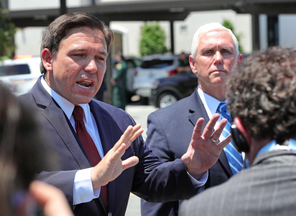 Gov. Ron DeSantis makes his point emphatically, as Vice President Mike Pence stands solemnly at his side.