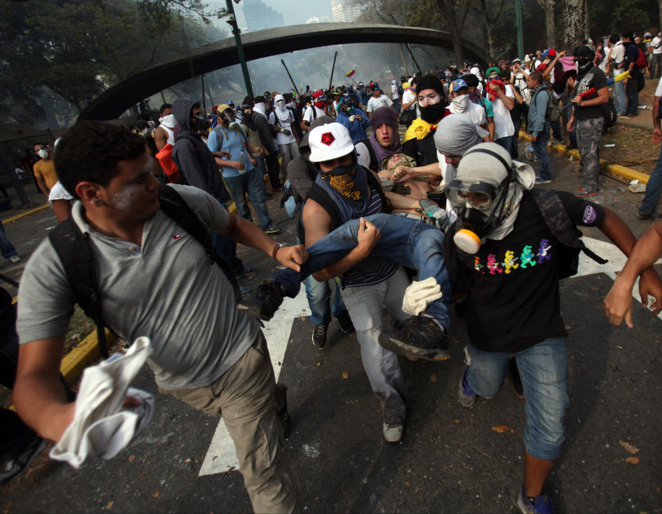 Un manifestante es evacuado herido en una pierna durante una protesta antigubernamental en Caracas, Venezuela, el miércoles 12 de marzo de 2014. (AP Photo/Alejandro Cegarra)