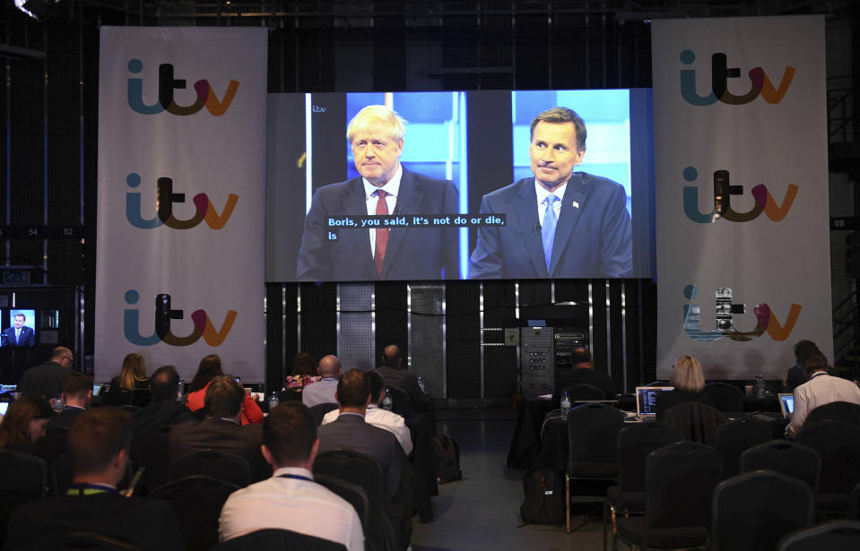 Journalists view the live TV debate between Conservative Party leadership candidates Boris Johnson, seen at left, and Jeremy Hunt, right, on a large screen at the ITV, TV studio in Salford, England, Tuesday July 9, 2019. (Stefan Rousseau/PA via AP)