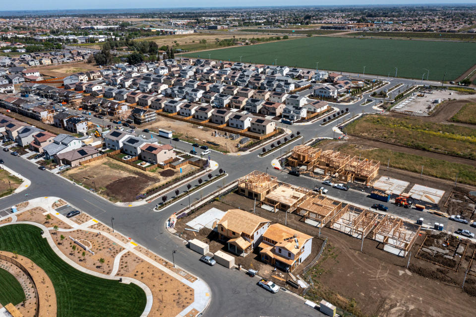 An aerial view of a large residential development, including empty lots and several homes under construction.