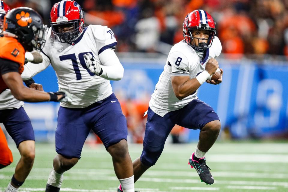 Then playing in high school for Southfield A&T, quarterback Isaiah Marshall runs against Belleville during the first half of the Division 1 state final at Ford Field in Detroit on Nov. 26, 2023.