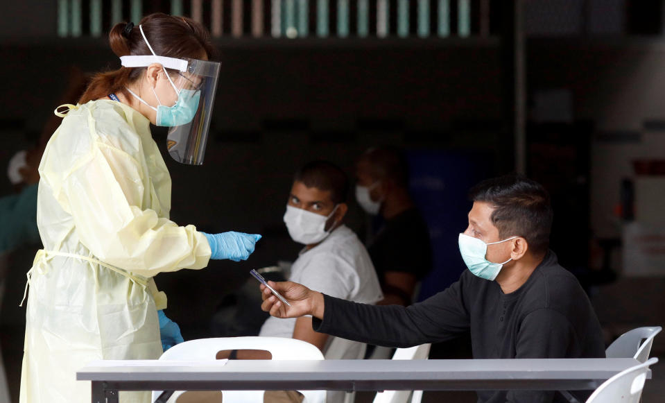 A medical professional talks to migrant workers as they wait to be transported to a medical facility from their dormitory, amid the coronavirus disease (COVID-19) outbreak, in Singapore April 27, 2020. REUTERS/Edgar Su