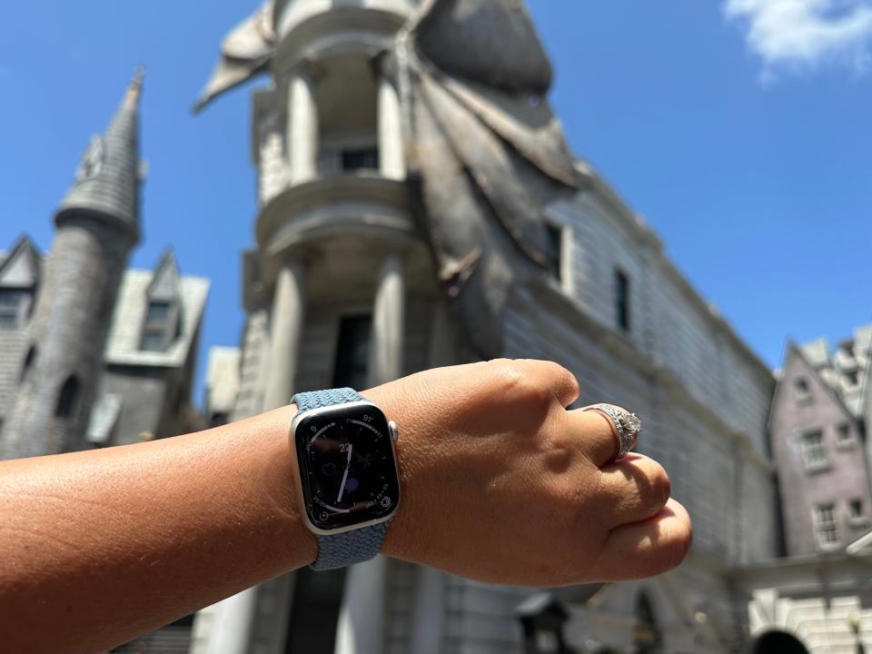 terri holing her apple watch up on her wrist in front of gringotts at wizarding world of harry potter in universal