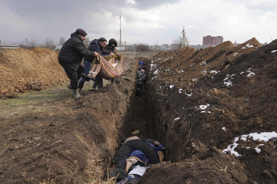 Cadáveres siendo arrojados a una fosa común en las afueras de Mariúpol, Ucrania, el 9 de marzo de 2022, ante la imposibilidad de enterrar a sus muertos debido a los intensos cañoneos de las fuerzas rusas. (AP Foto/Evgeniy Maloletka)