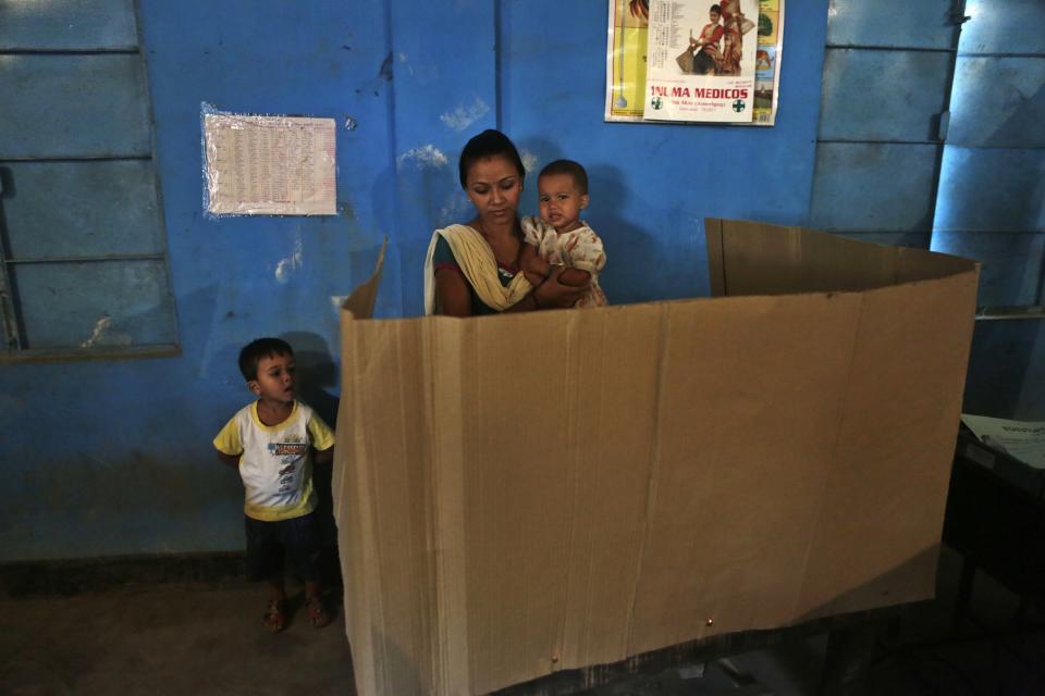 An Indian boy watches as his mother casts her vote during the sixth phase of polling of the Indian parliamentary elections in Gauhati, India, Thursday, April 24, 2014.The multiphase voting across the country runs until May 12, with results for the 543-seat lower house of parliament expected on May 16. (AP Photo/Anupam Nath)