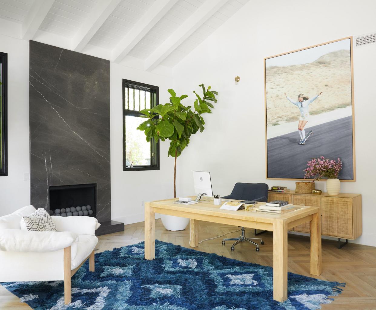beachy home office with blue rug, large art, and wooden desk