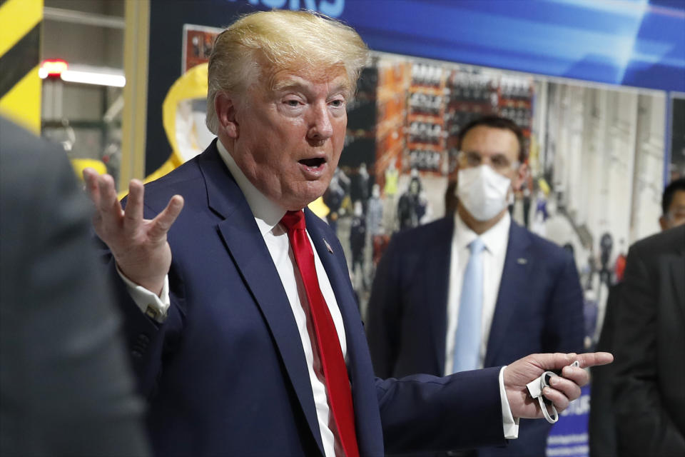 FILE - In this May 21, 2020 file photo, President Donald Trump holds a face mask in his left hand as he speaks during a tour of Ford's Rawsonville Components Plant that has been converted to making personal protection and medical equipment, in Ypsilanti, Mich. From the U.S. president to the British prime minister's top aide and far beyond, leading officials around the world are refusing to wear masks or breaking confinement rules meant to protect their populations from the coronavirus and slow the pandemic. While some are punished when they're caught, or publicly repent, others shrug off the violations as if the rules don't apply to them. (AP Photo/Alex Brandon, File)