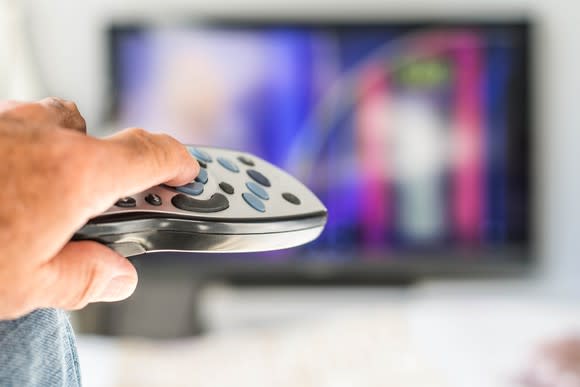A person pointing a remote at a television