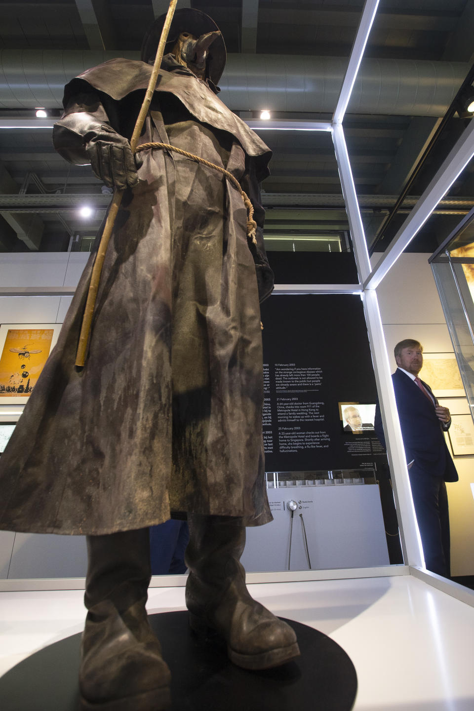 Dutch King Willem-Alexander, rear right, looks at a replica of a plague doctor's long robe as he tours the "Contagious!" exhibit at Rijksmuseum Boerhave in Leiden, Netherlands, Thursday, July 16, 2020. The museum finally opened an exhibition Thursday on contagious diseases through the ages after a long delay caused by the disease currently sweeping the world, COVID-19. (AP Photo/Peter Dejong, Pool)