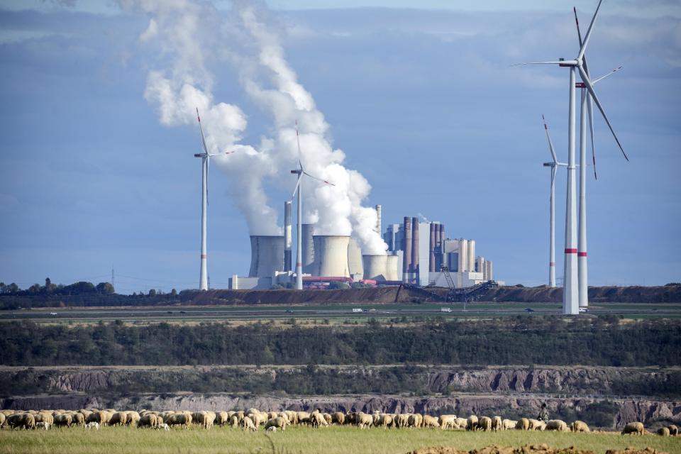 FILE - A flock of sheep graze in front of a coal-fired power plant at the Garzweiler open-cast coal mine near Luetzerath, western Germany, Sunday Oct. 16, 2022. About 1,000 miles away from Ukraine, Luetzerath is an indirect victim of the war as the town will soon make way for the expansion of a nearby coal mine. Environmentalists have been up in arms about the decision which would pump millions more tons of planet-warming carbon dioxide into the air. (AP Photo/Martin Meissner, File)