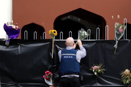 A police officer places flowers at the entrance of Masjid Al Noor mosque in Christchurch, New Zealand, March 17, 2019. REUTERS/Jorge Silva