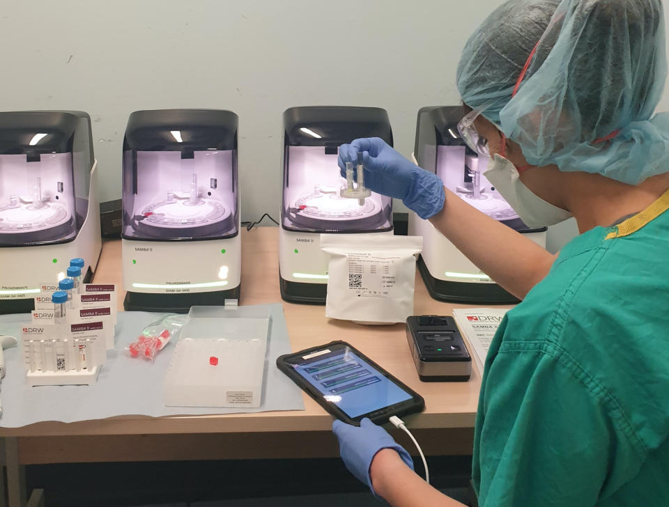 Undated handout photo issued by Cambridge University Hospitals showing research nurses from the NIHR Clinical Research Facility processing patient samples using SAMBA II testing machines at Addenbrookeâs Hospital in Cambridge.