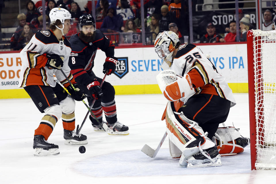 Anaheim Ducks goaltender John Gibson (36) watches the puck as teammate Trevor Zegras (11) and Carolina Hurricanes' Brent Burns (8) close in during the second period of an NHL hockey game in Raleigh, N.C., Saturday, Feb. 25, 2023. (AP Photo/Karl B DeBlaker)