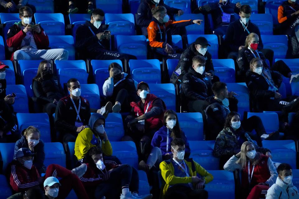 Athletes wearing face masks to protect against COVID-19 and sitting distanced from each other watch the action at the ISU World Cup Short Track speed skating competition, a test event for the 2022 Winter Olympics, at the Capital Indoor Stadium in Beijing, Sunday, Oct. 24, 2021.