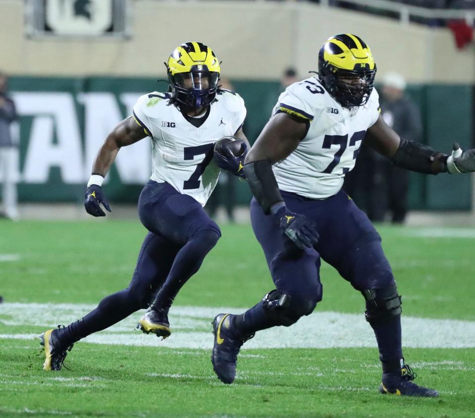 Michigan Wolverines offensive lineman LaDarius Henderson (73) blocks for Michigan Wolverines running back Donovan Edwards (7) during first-half action at Spartan Stadium in East Lansing on Saturday, Oct. 21, 2023.