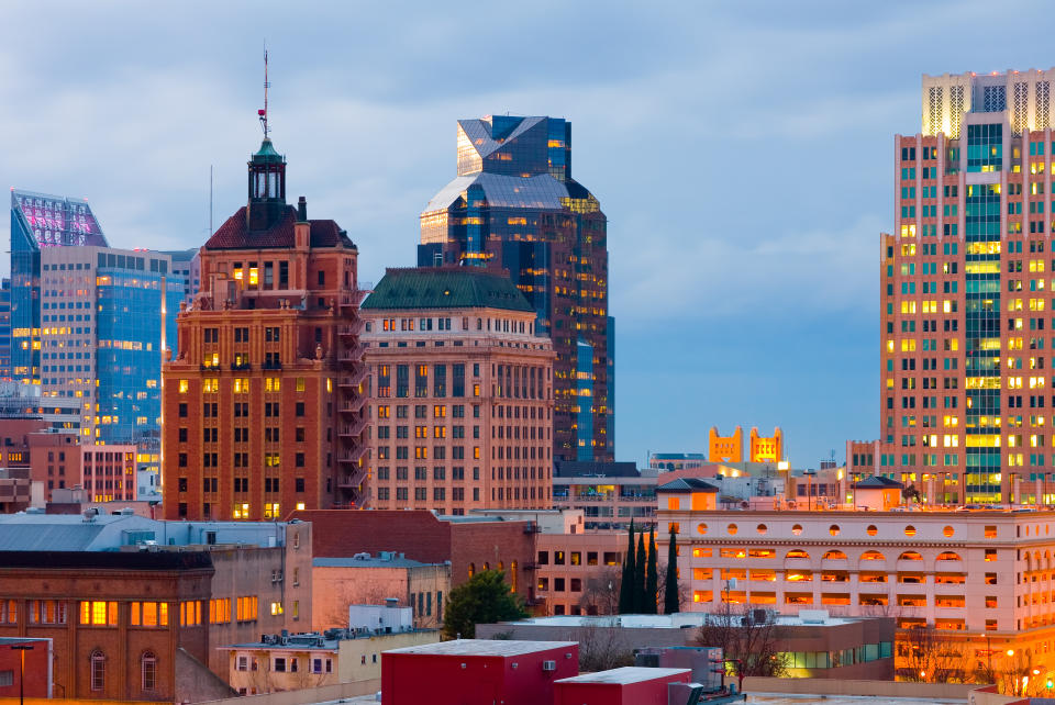 A urban skyline in Sacramento where newer office buildings and old apartments adjoin.