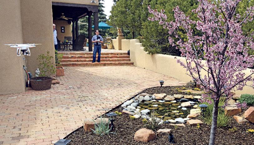 Santa Fe, New Mexico homeowner Hal Wingo, left, watches as Brian Tercero, of Keller Williams Realty flies his DJI Phantom drone as he takes video of the garden on April 18, 2014, in Santa Fe, N.M. (AP Photo/The Santa Fe New Mexican, Clyde Mueller)