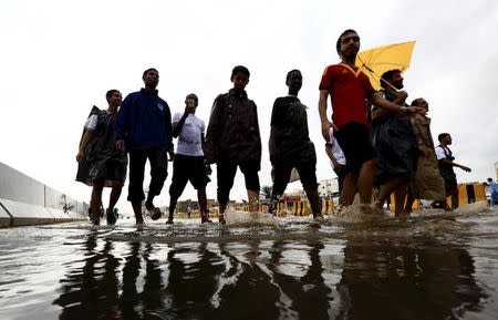 People walk through a flooded street following heavy rain in Jeddah, Saudi Arabia November 17, 2015. REUTERS/Mohamed Al Hwaity