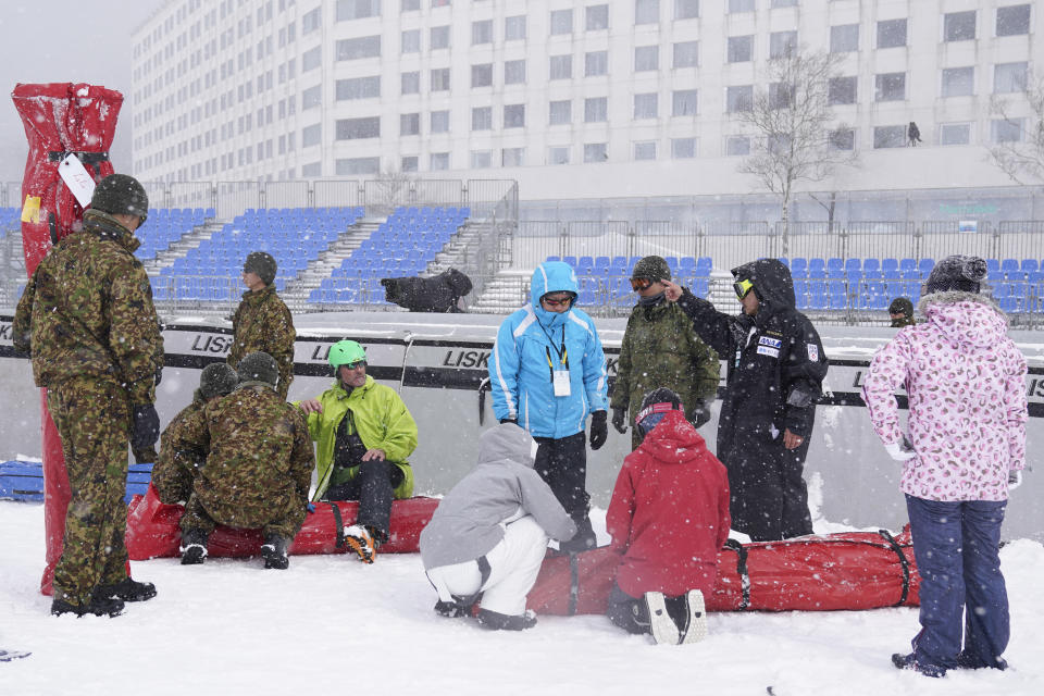 Japan Self-Defense Forces members and event staff officials prepare to put away signage after it was announced that the men's slalom race has been cancelled due to weather conditions during the 2020 Audi FIS Alpine Ski World Cup at Naeba Ski Resort in Yuzawa, Niigata prefecture, northern Japan, Sunday, Feb. 23, 2020. (AP Photo/Christopher Jue)