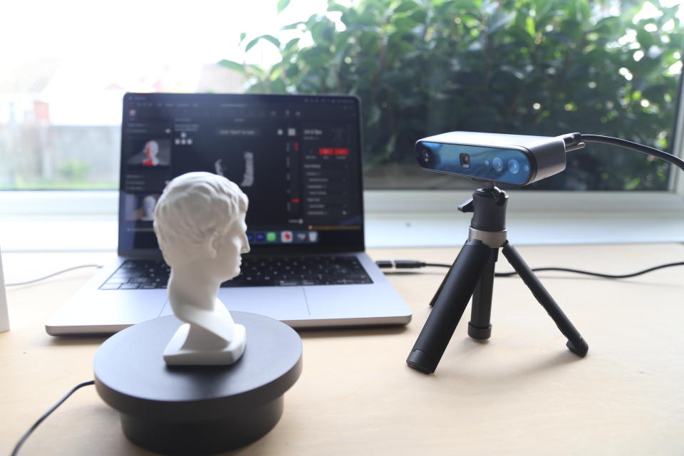 A Revopoint INSPIRE 3D Scanner on a desk, along with an object to scan and a laptop