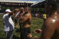 An 'oiler', someone charged with oiling up wrestlers and filling up oil pitchers, douses wrestlers in olive oil, during the 660th instalment of the annual Historic Kirkpinar Oil Wrestling championship, in Edirne, northwestern Turkey, Saturday, July 10, 2021.Thousands of Turkish wrestling fans flocked to the country's Greek border province to watch the championship of the sport that dates to the 14th century, after last year's contest was cancelled due to the coronavirus pandemic. The festival, one of the world's oldest wrestling events, was listed as an intangible cultural heritage event by UNESCO in 2010. (AP Photo/Emrah Gurel)