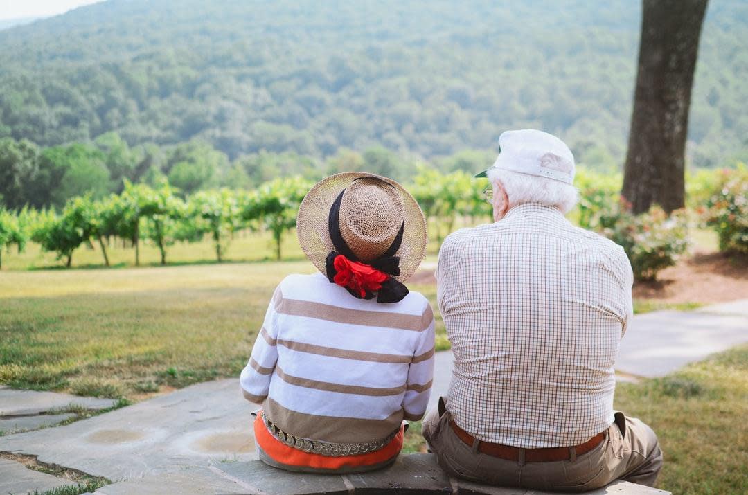 Alzheimer's An older couple sitting and looking out at vineyard-like nature. (Stock Image)