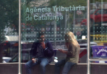 A couple is reflected on a glass of the Catalan Tax Agency in Barcelona, Spain, September 18, 2017. REUTERS/Albert Gea