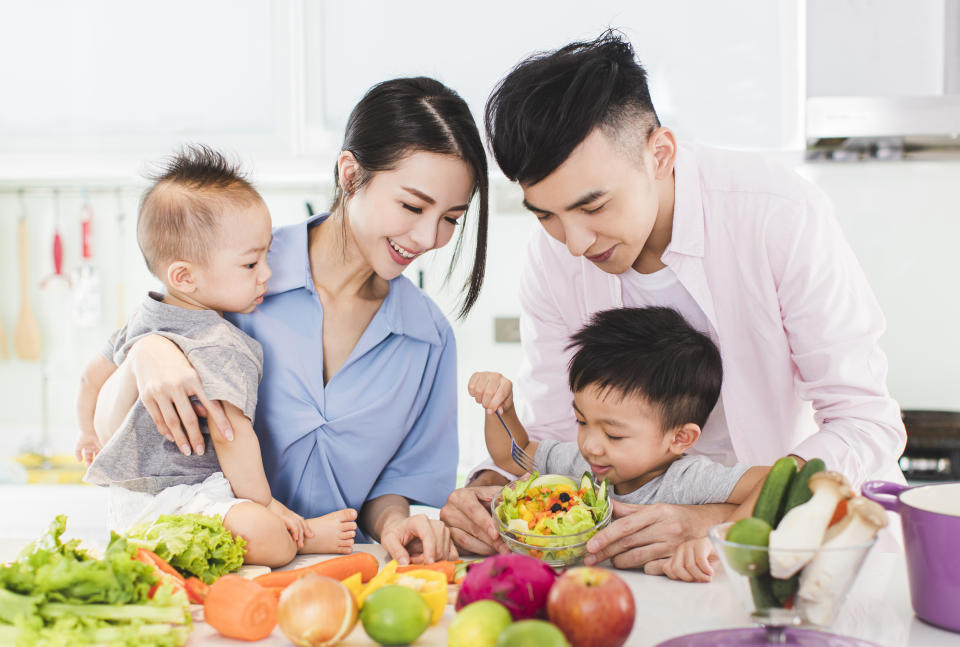 A couple prepares a healthy meal for themselves and their kids in the kitchen