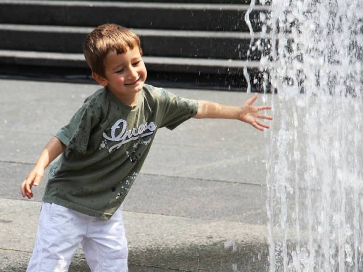 A child is pictured here playing in the splash pad at Yonge-Dundas Square in Toronto.  (Asha Siad/CBC - image credit)