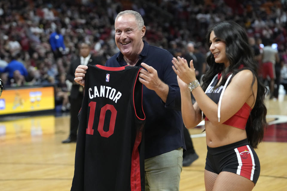 Soccer announcer Andres Cantor, left, is presented with a Miami Heat jersey during the first half of an NBA basketball game between the Miami Heat and the Washington Wizards, Sunday, March 10, 2024, in Miami. (AP Photo/Lynne Sladky)