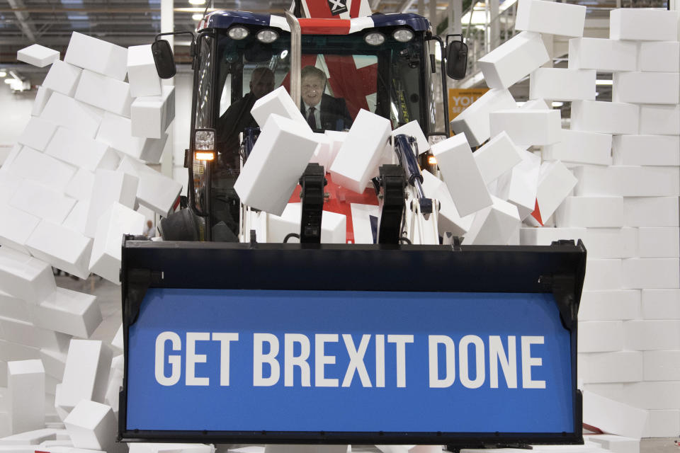 Britain's Prime Minister Boris Johnson sits in the cab to break through a symbolic wall with the Conservative Party slogan 'Get Brexit Done', during an election campaign event at the JCB manufacturing facility in Uttoxeter, England, Tuesday Dec. 10, 2019. The Conservative Party are campaigning for their Brexit split with Europe ahead of the UK's General Election on Dec. 12. (Stefan Rousseau/PA via AP)