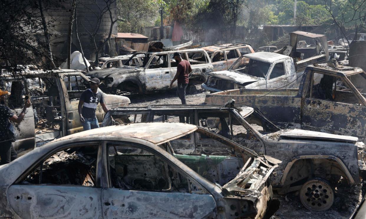<span>People look for salvageable pieces from burned cars at a shop that was set on fire by armed gangs in Port-au-Prince on 25 March.</span><span>Photograph: Odelyn Joseph/AP</span>