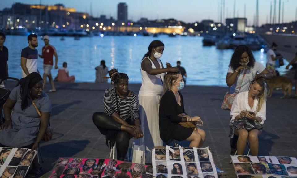 People have their hair braided at the old port in Marseille.