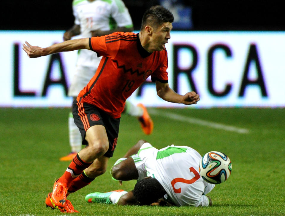 Nigeria's Godfrey Oboabona (2) grabs his injured knee and falls to the turf as Mexico's Oribe Peralta (19) dribbles past during the first half of an international friendly soccer match Wednesday, March 5, 2014, in Atlanta. (AP Photo/David Tulis)