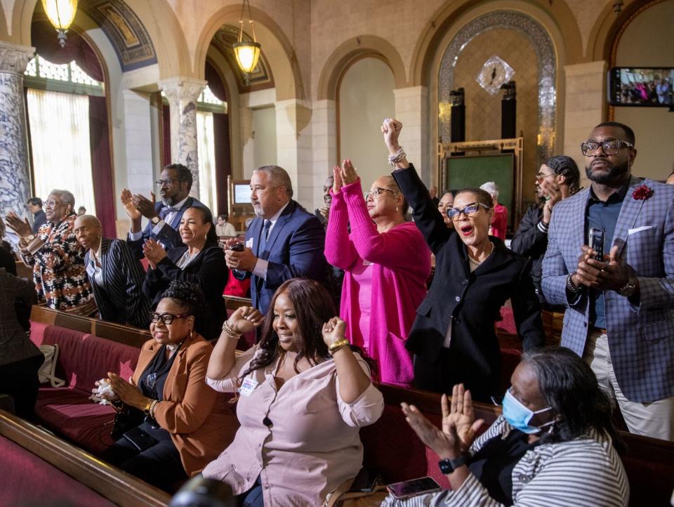 Supporters in the benches of a government hall cheer, some rising out of their seats