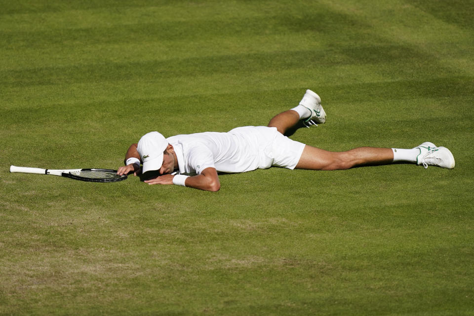 Serbia's Novak Djokovic lays on the court after falling making a return to Britain's Cameron Norrie in a men's singles semifinal on day twelve of the Wimbledon tennis championships in London, Friday, July 8, 2022. (AP Photo/Gerald Herbert)