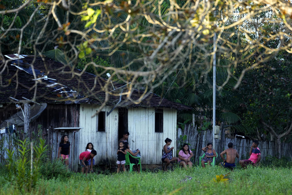 Indigenous Tembe family members sit and talk in front of their house at dusk, in the Tenetehar Wa Tembe village in the Alto Rio Guama Indigenous territory, in Paragominas municipality, in Para state, Brazil, Monday, May 29, 2023. (AP Photo/Eraldo Peres)