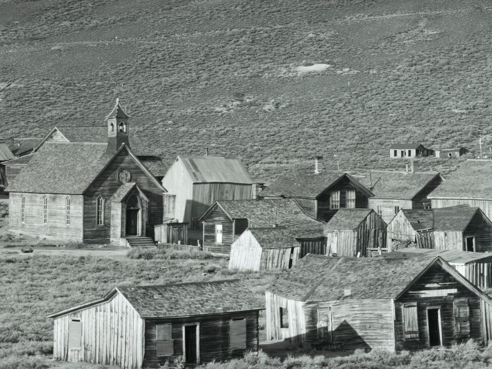 black and white photo of bodie, california, where there are a few buildings in an open field
