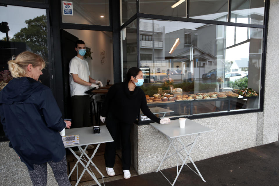 AUCKLAND, NEW ZEALAND - AUGUST 25: Staff at Honey Bones cafe in Grey Lynn serve takeaway customers at level three lockdown on August 25, 2020 in Auckland, New Zealand. Auckland will remain at level three COVID-19 restriction levels until Monday, August 31, when it will downgrade to level two with the rest of New Zealand. (Photo by Fiona Goodall/Getty Images)